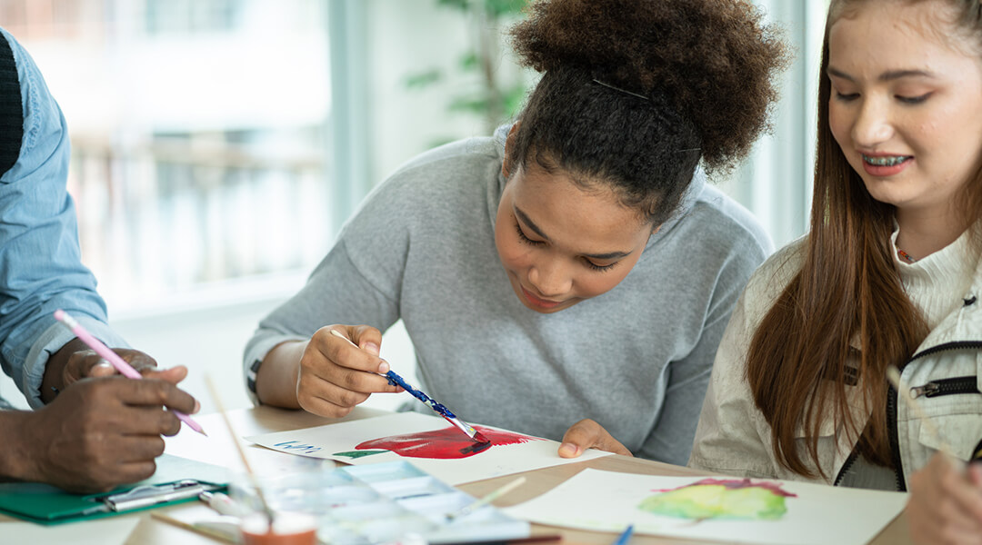 Two tweens paint together at a table.