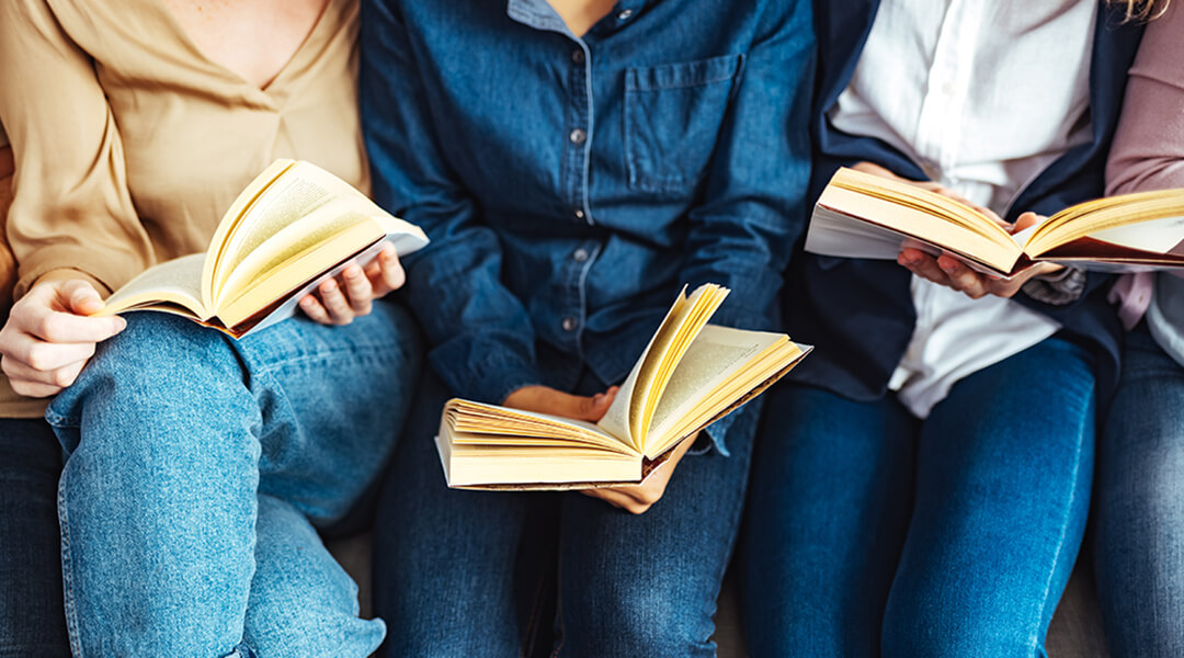 Diverse group of friends discussing a book in library.