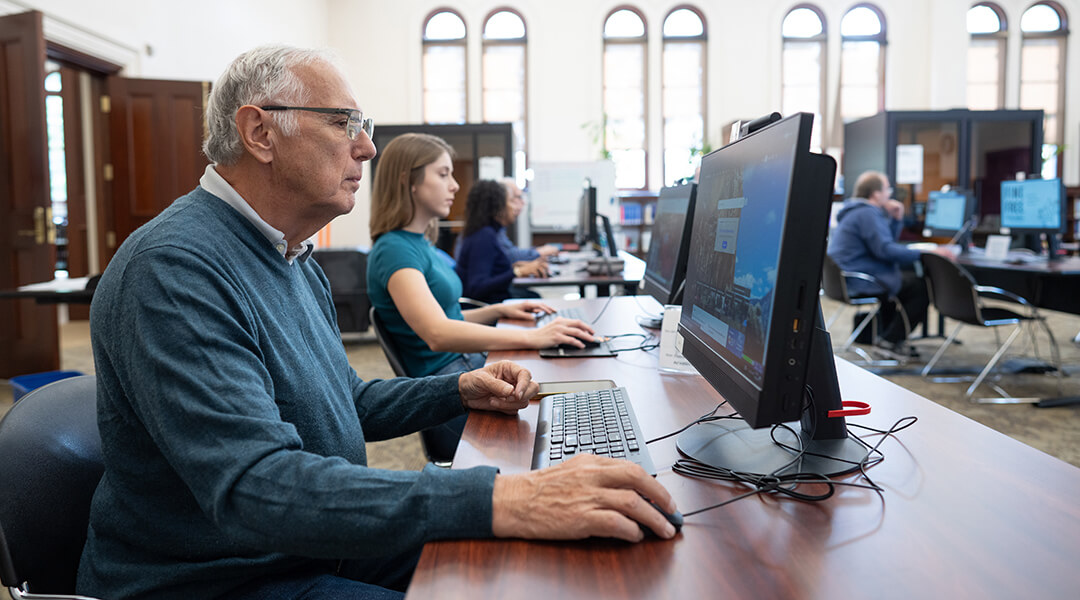 A senior adult uses a public computer at the library.