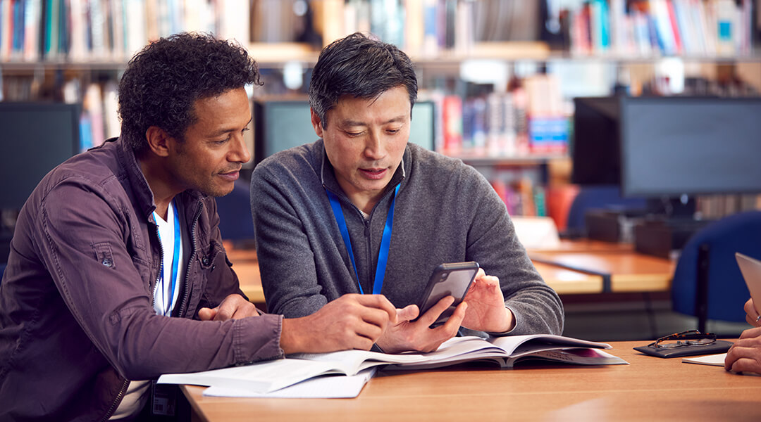 A librarian assists an adult patron with their cell phone.