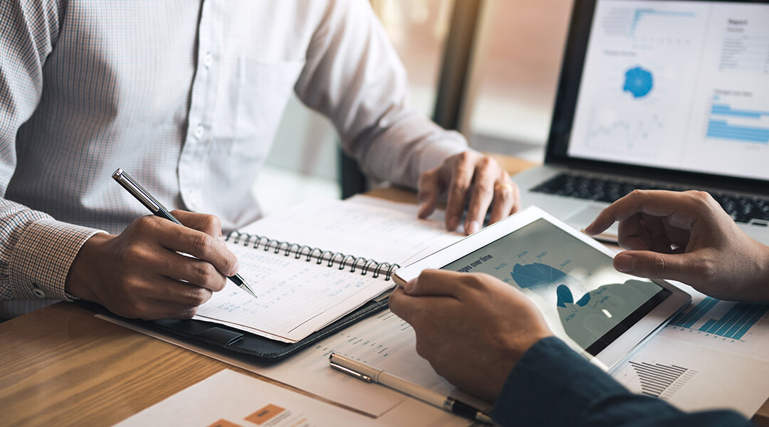 Two business partners discussing a financial planning graph and company during a budget meeting in office room.