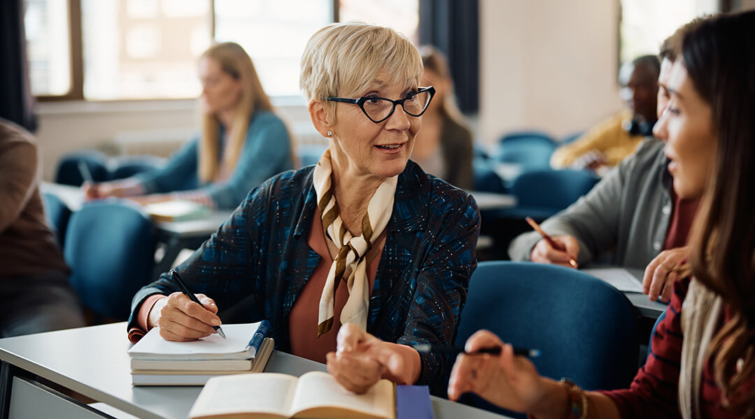 Mature adult talking to younger classmate during an educational course in the classroom.