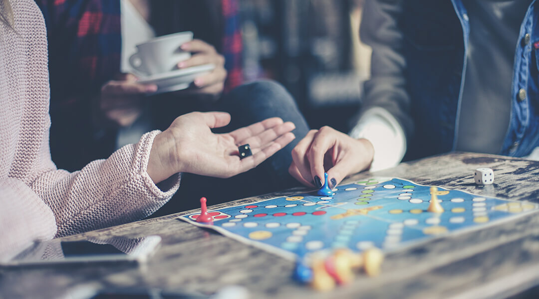 Three adults play a board game together.