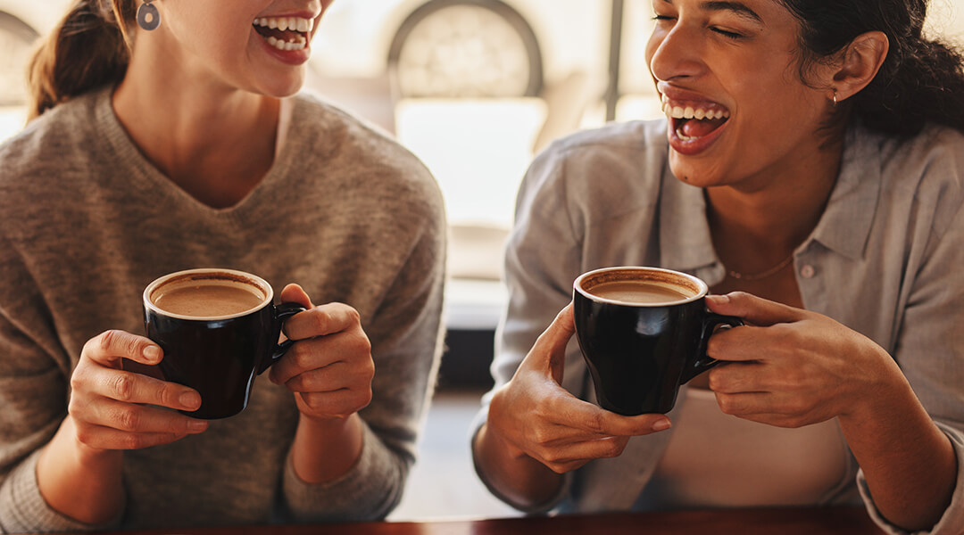 Two adults sitting at a coffee table talking and laughing.