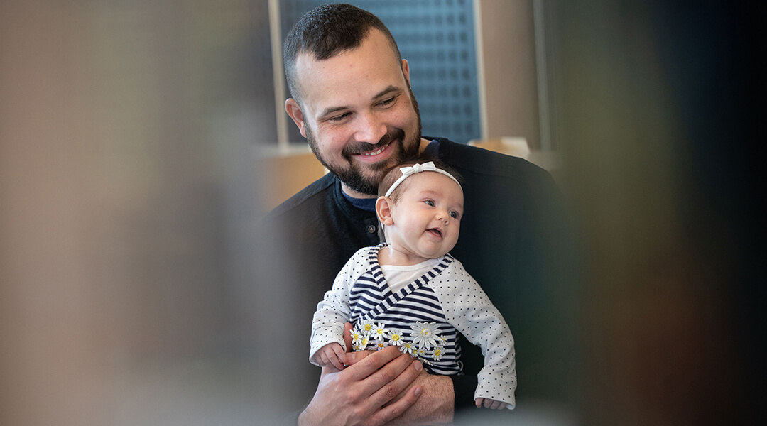 An adult holds an infant on their lap during storytime.