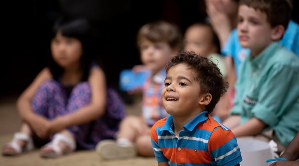 A group of children, between three and five, listen to a storytime presentation.