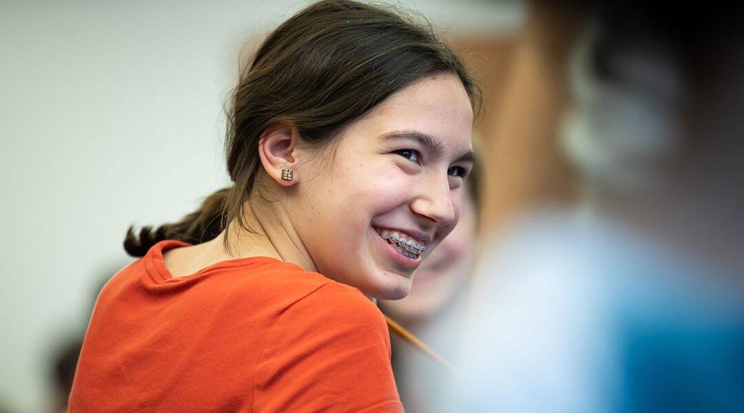 Close-up of a smiling teenager with braces at a library event.