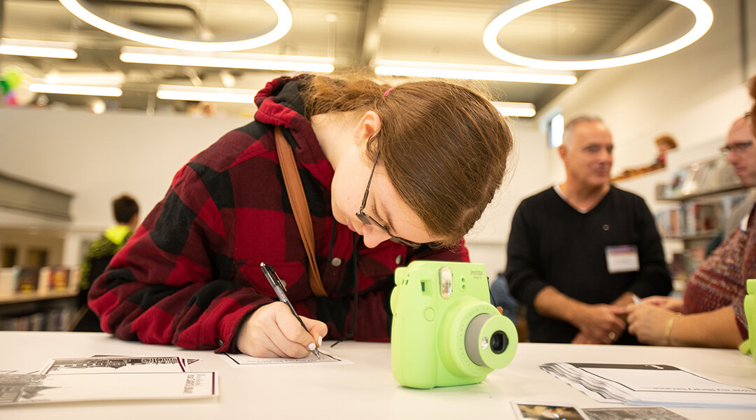 A teen writes a caption for the picture they've taken with an instant camera.